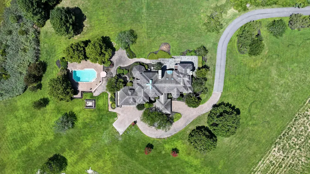 Overhead aerial view of the house, pool and winding drive surrounded by open land