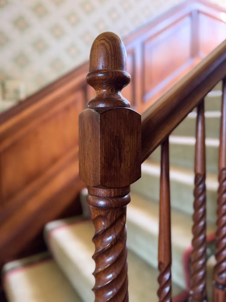 A turned wood newel post and twisted balusters on the stair