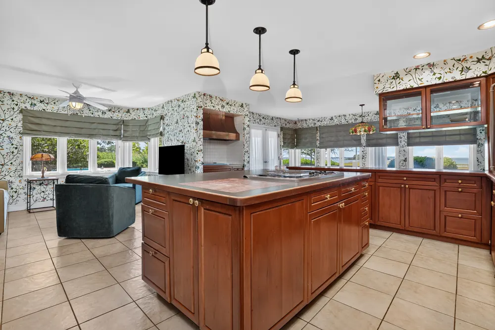 The eat-in kitchen with wood cabinetry, a large island and pendant lights