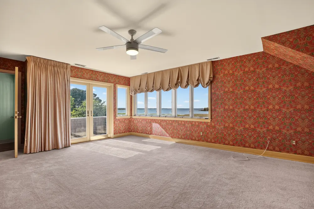 The primary bedroom on the bay front, with windows and French doors facing the water